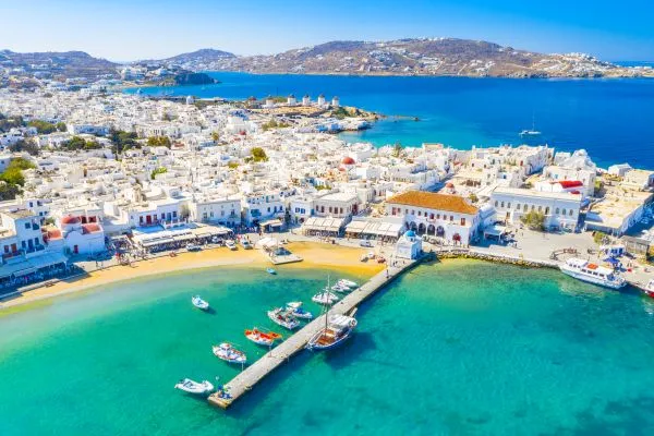 Iconic view of the legendary windmills of Mykonos overlooking Little Venice and the Aegean Sea, a symbol of the Cyclades' most luxurious vacation destinations.