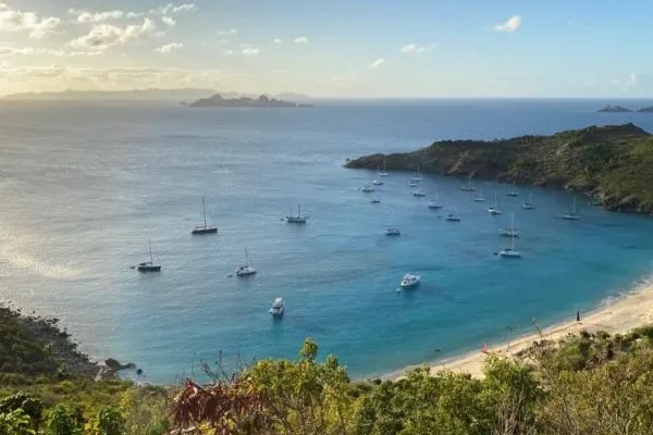 Vue aérienne de Saint-Barthélemy, l’une des destinations de voyage de luxe les plus prisées des Caraïbes, montrant ses eaux turquoise bordées de collines verdoyantes.