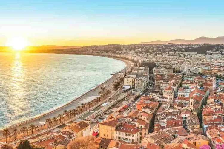 Sunset view over Nice’s Baie des Anges with red-tiled rooftops and ochre facades of the old town overlooking the Mediterranean, highlighting Nice as one of France’s top luxury travel destinations.